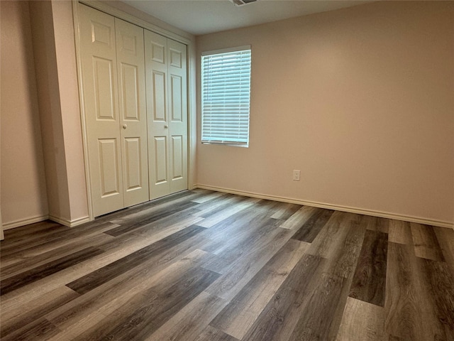 unfurnished bedroom featuring dark wood-type flooring and a closet