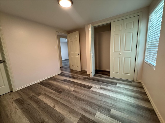 unfurnished bedroom with dark hardwood / wood-style flooring and a closet