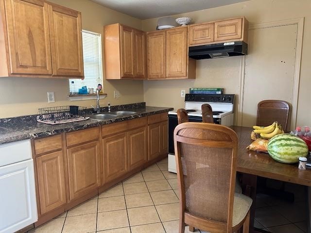 kitchen featuring sink, light tile patterned flooring, white range with electric cooktop, and dark stone counters