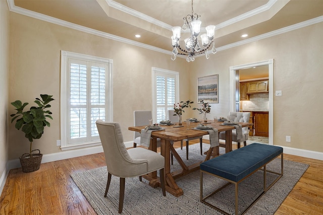 dining space with plenty of natural light, crown molding, light wood-type flooring, and a tray ceiling