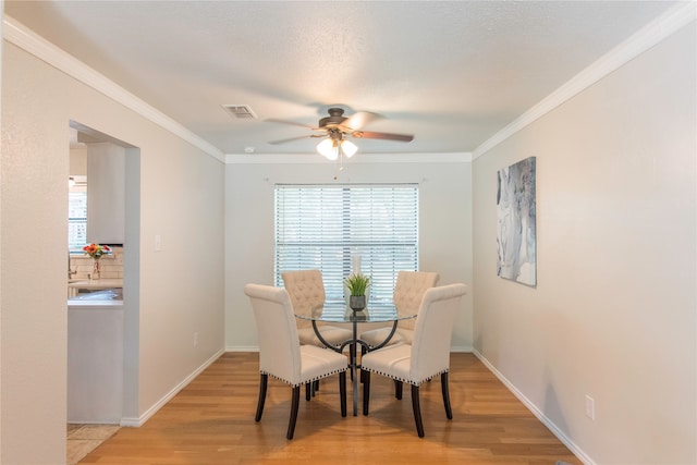 dining room featuring light hardwood / wood-style floors, ceiling fan, and crown molding