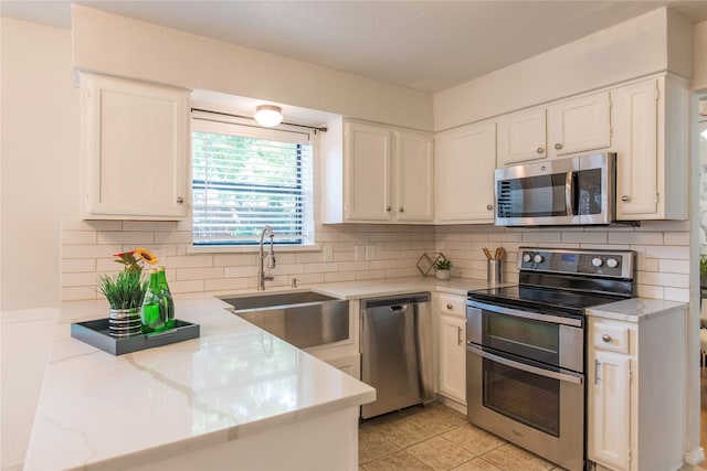 kitchen with decorative backsplash, white cabinetry, sink, and stainless steel appliances