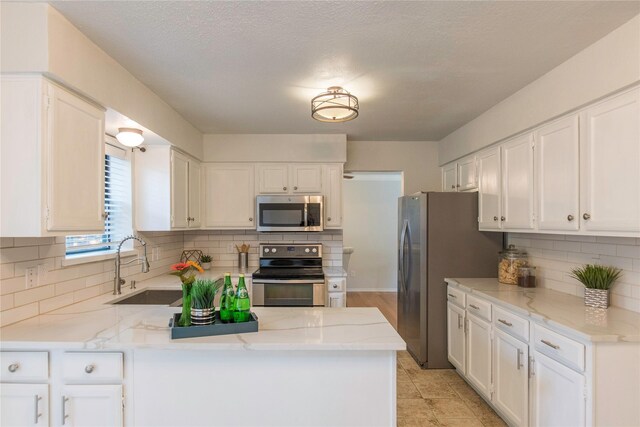 kitchen featuring kitchen peninsula, white cabinetry, sink, and appliances with stainless steel finishes