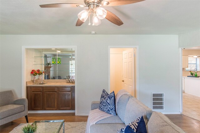 living room with ceiling fan, light wood-type flooring, and sink