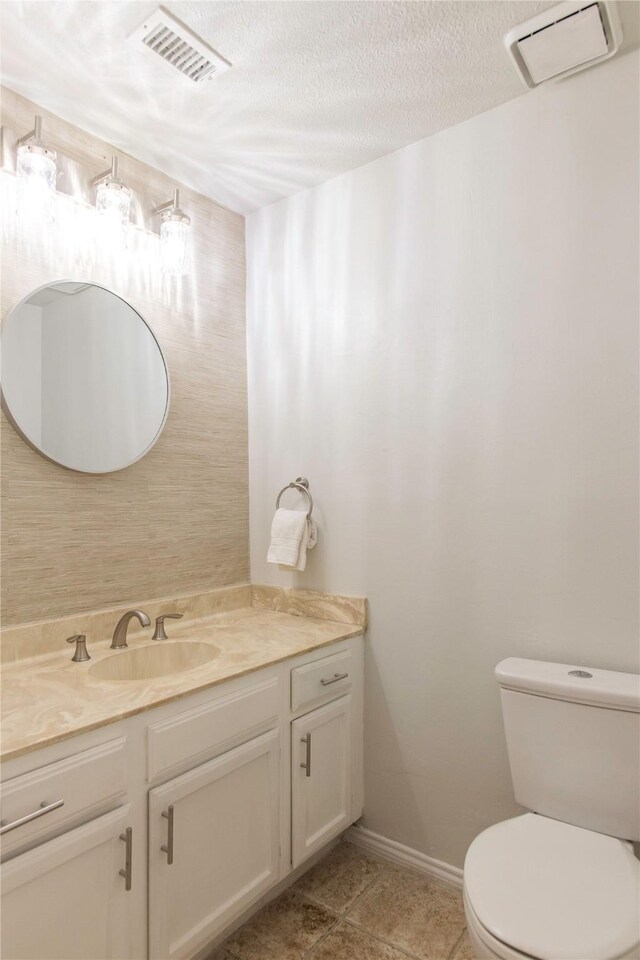 bathroom featuring a textured ceiling, vanity, and toilet