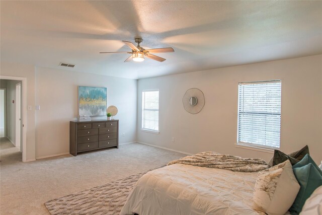 bedroom with multiple windows, light carpet, and ceiling fan