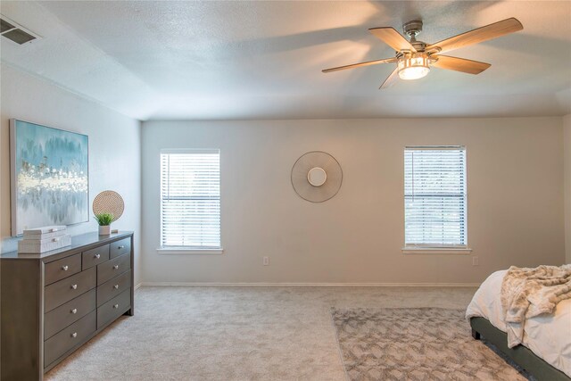 bedroom with multiple windows, ceiling fan, light colored carpet, and a textured ceiling