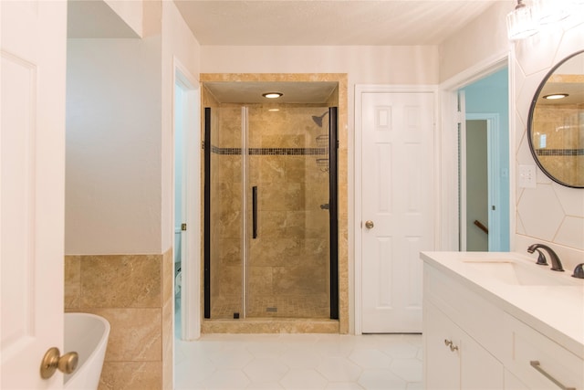 bathroom featuring tile patterned flooring, vanity, tile walls, and plus walk in shower