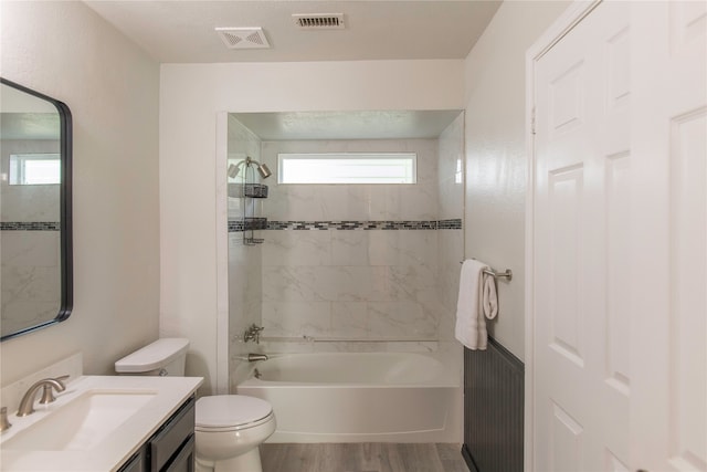 full bathroom featuring hardwood / wood-style flooring, vanity, toilet, and tiled shower / bath combo