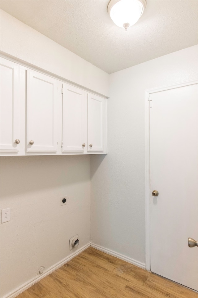 laundry room featuring electric dryer hookup, cabinets, and light hardwood / wood-style floors