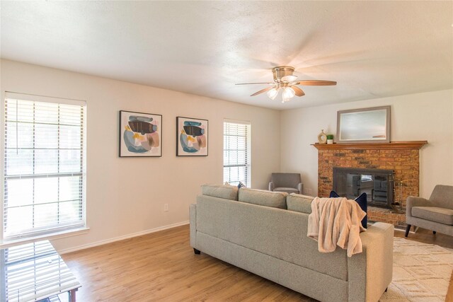 living room with a wood stove, ceiling fan, and light hardwood / wood-style flooring