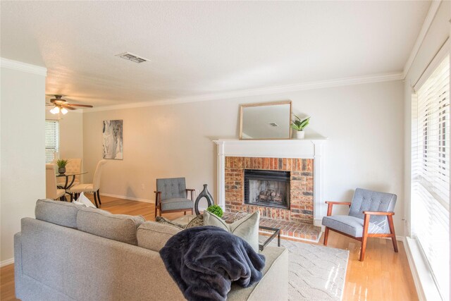 living room featuring ornamental molding, a fireplace, and light hardwood / wood-style flooring