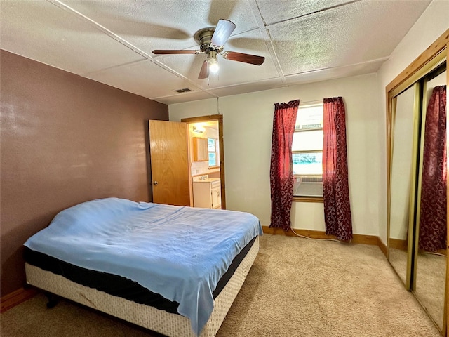 carpeted bedroom with a closet, ensuite bath, and ceiling fan