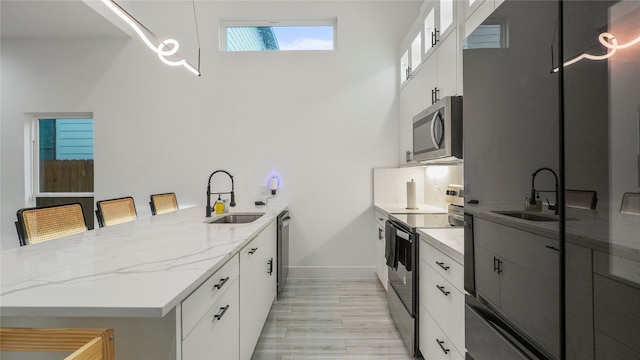 kitchen featuring sink, light stone counters, white cabinets, and stove