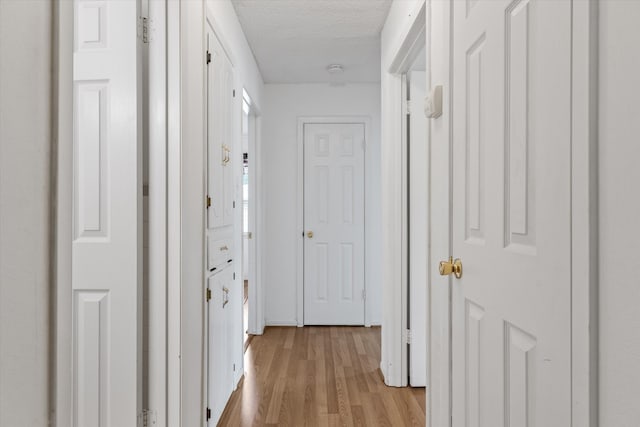 corridor with light hardwood / wood-style floors and a textured ceiling