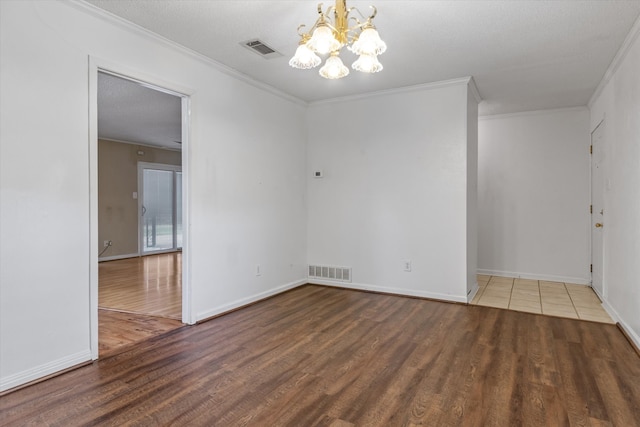 empty room with a chandelier, a textured ceiling, wood-type flooring, and ornamental molding