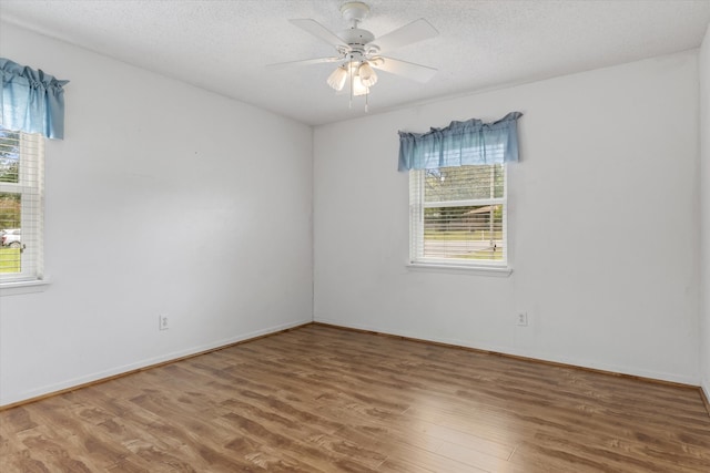 unfurnished room featuring hardwood / wood-style flooring, a wealth of natural light, and ceiling fan