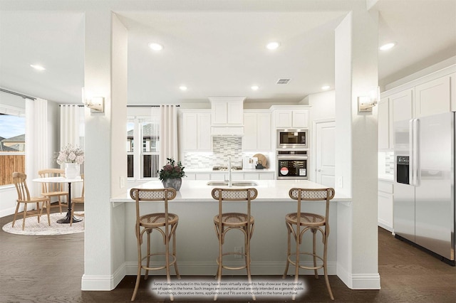 kitchen featuring appliances with stainless steel finishes, a breakfast bar, white cabinets, and kitchen peninsula