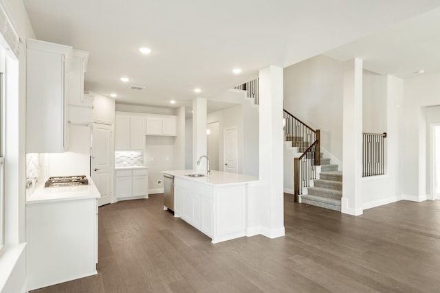 kitchen featuring sink, white cabinetry, stainless steel appliances, a center island with sink, and decorative backsplash