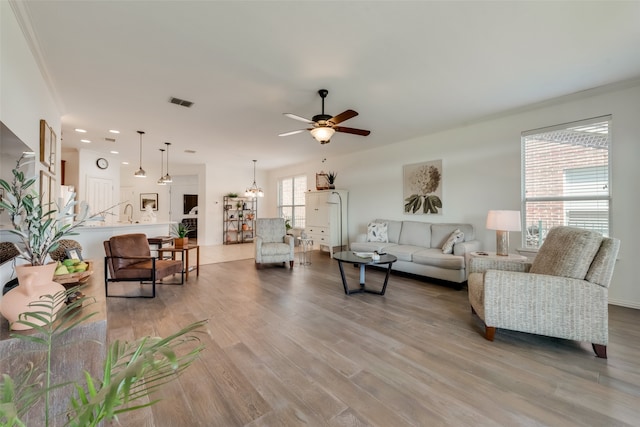 living room featuring light hardwood / wood-style floors, ceiling fan, and crown molding