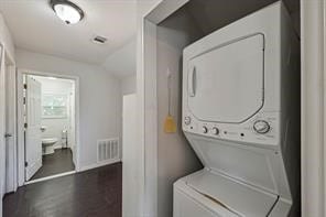 washroom with wood-type flooring and stacked washer and clothes dryer