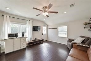 living room with ceiling fan, vaulted ceiling, dark wood-type flooring, and a healthy amount of sunlight