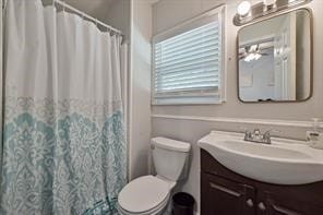 bathroom featuring toilet, vanity, and ceiling fan