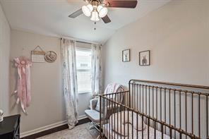 bedroom featuring radiator heating unit, a crib, vaulted ceiling, and ceiling fan