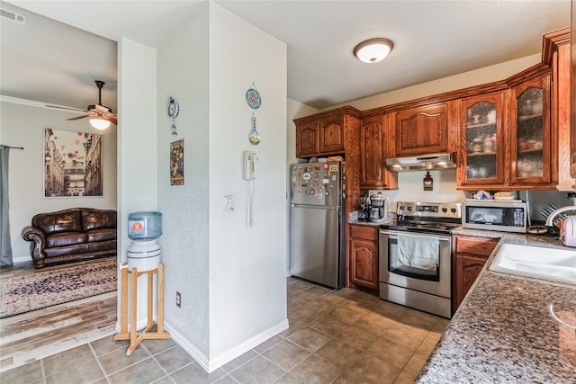 kitchen with dark stone counters, appliances with stainless steel finishes, sink, and ceiling fan