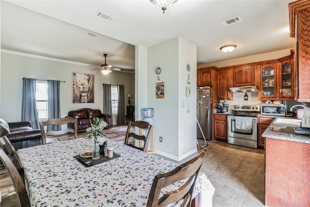 tiled dining space featuring crown molding, ceiling fan, and sink