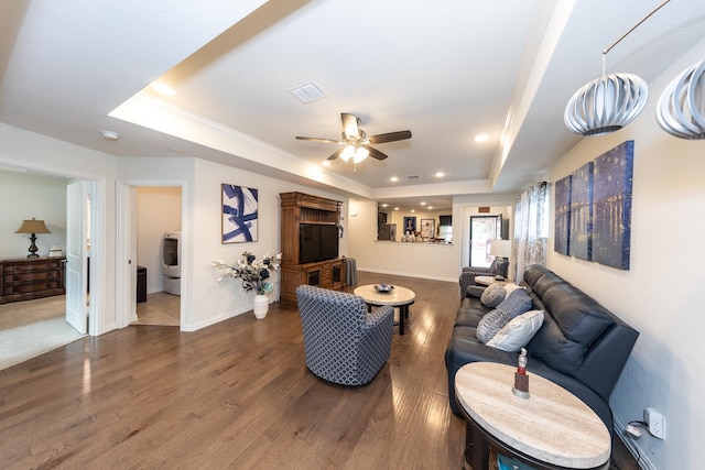 living room with washer / dryer, crown molding, dark hardwood / wood-style flooring, a tray ceiling, and ceiling fan