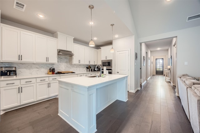 kitchen with appliances with stainless steel finishes, pendant lighting, white cabinetry, an island with sink, and sink