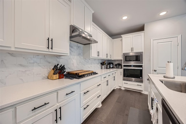 kitchen with sink, backsplash, stainless steel appliances, light stone countertops, and white cabinets