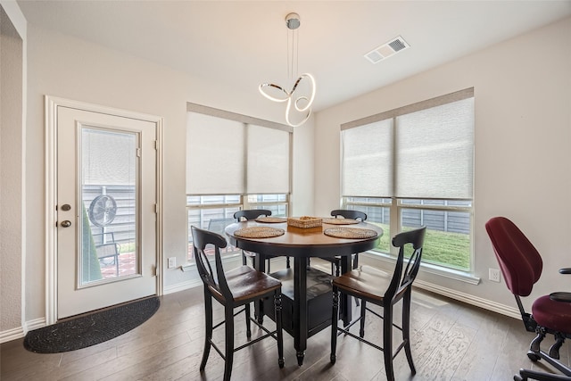 dining area featuring a notable chandelier, a wealth of natural light, and dark wood-type flooring