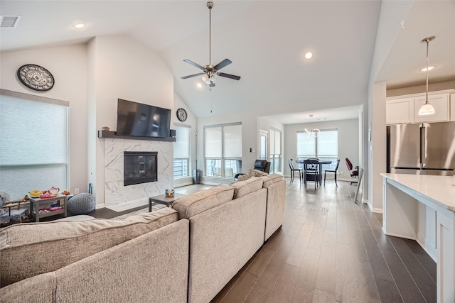 living room with ceiling fan, a high end fireplace, dark hardwood / wood-style floors, and high vaulted ceiling