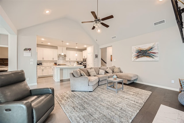 living room featuring hardwood / wood-style floors, high vaulted ceiling, sink, and ceiling fan