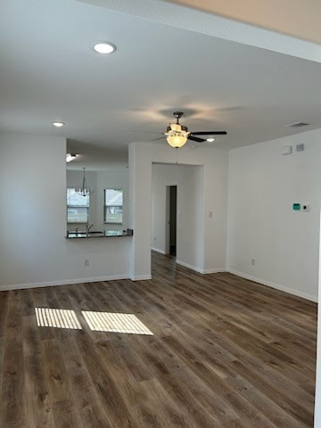 unfurnished living room with ceiling fan with notable chandelier and dark hardwood / wood-style floors