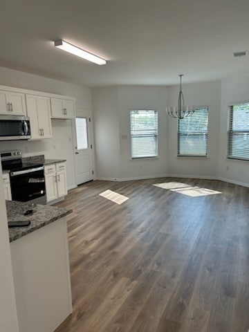 kitchen featuring appliances with stainless steel finishes, hanging light fixtures, white cabinetry, and dark hardwood / wood-style flooring