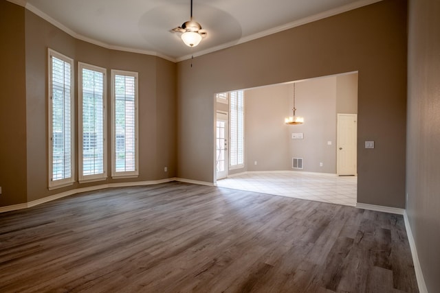 spare room featuring ceiling fan with notable chandelier, crown molding, and hardwood / wood-style floors