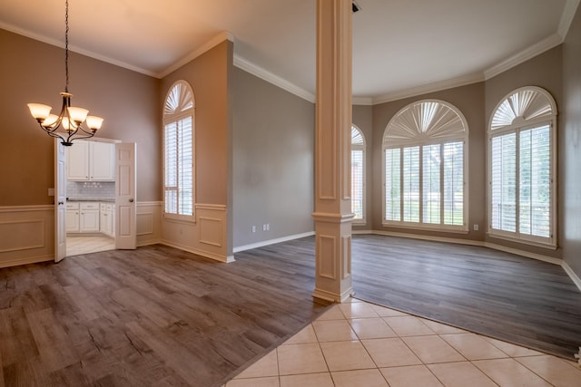 interior space with light hardwood / wood-style flooring, an inviting chandelier, a wealth of natural light, and crown molding