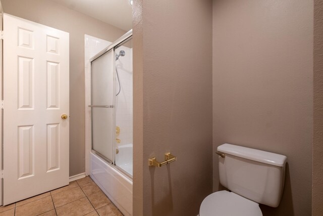 bathroom with tile patterned flooring, toilet, and enclosed tub / shower combo