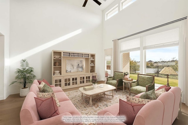 living room with ceiling fan, a healthy amount of sunlight, hardwood / wood-style floors, and a high ceiling