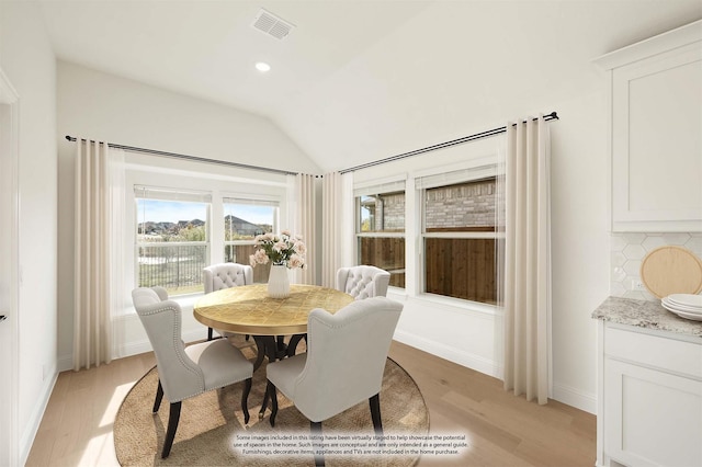 dining room with vaulted ceiling and light wood-type flooring