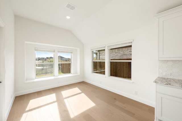 unfurnished dining area with light hardwood / wood-style floors and lofted ceiling