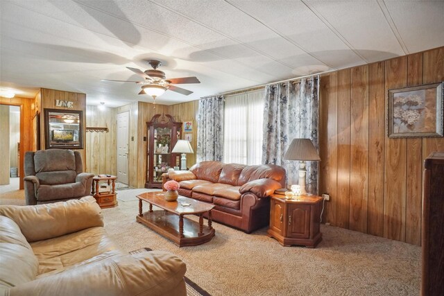 carpeted living room featuring ceiling fan and wooden walls