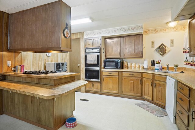 kitchen with stainless steel gas stovetop, white dishwasher, light tile patterned flooring, sink, and double oven