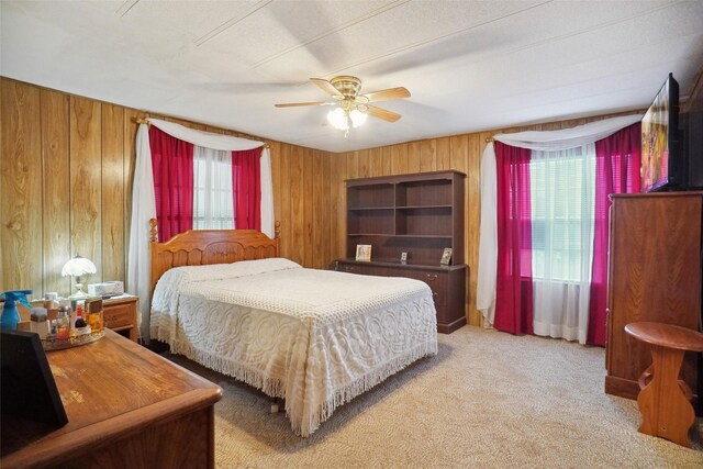 carpeted bedroom with wood walls and ceiling fan