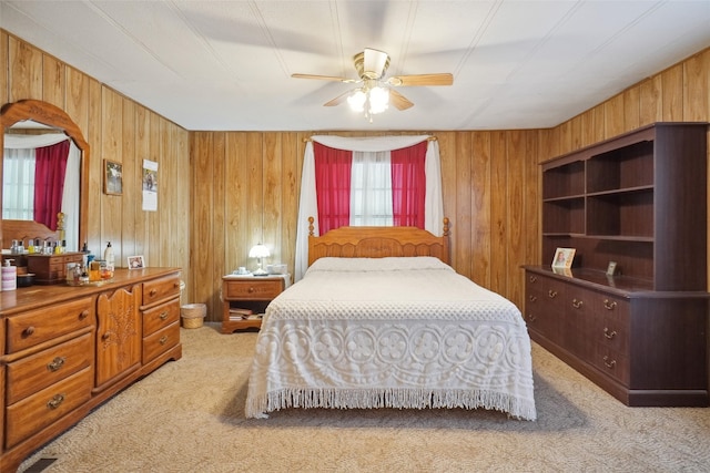 carpeted bedroom with wooden walls and ceiling fan