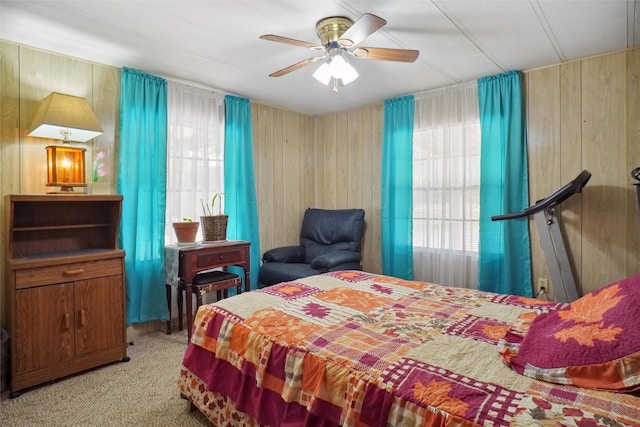 carpeted bedroom with ceiling fan and wooden walls