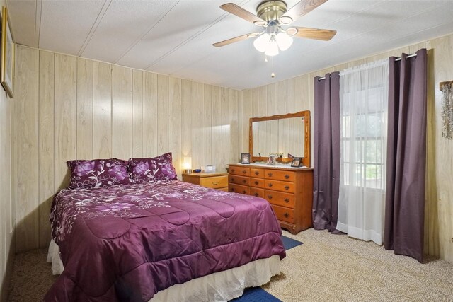 bedroom with wood walls, carpet flooring, and ceiling fan